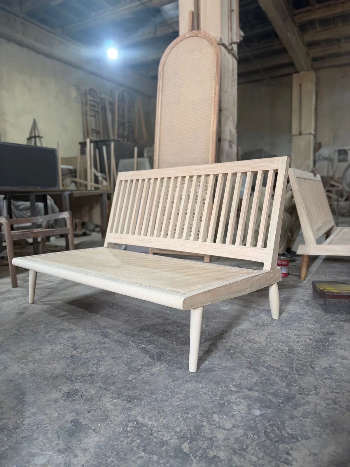 A raw wooden bench frame drying under workshop lights